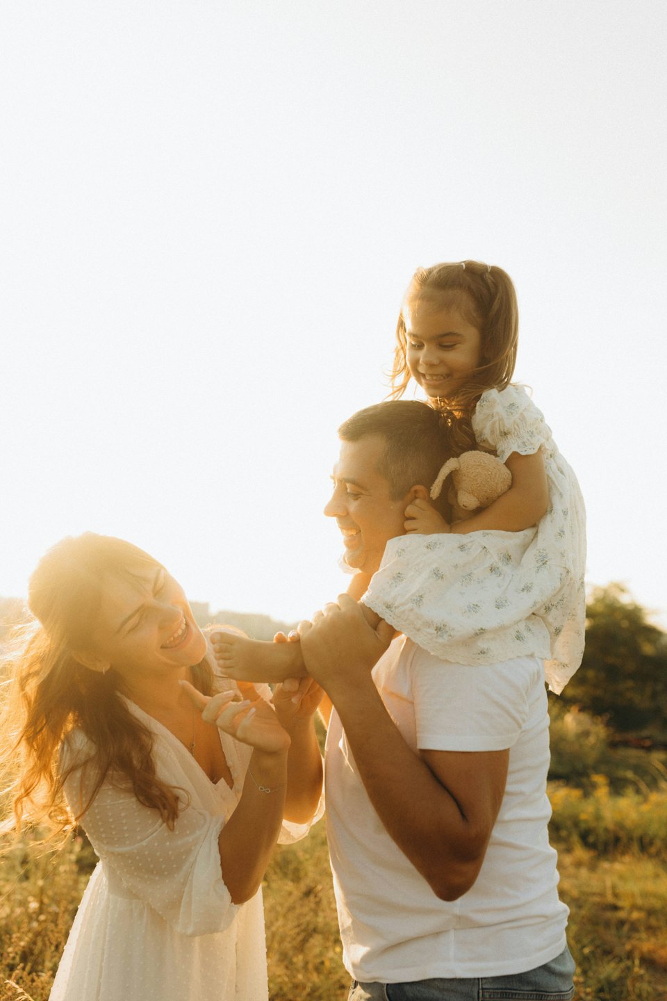 Rodzina śmieje się, spacerując po łące.