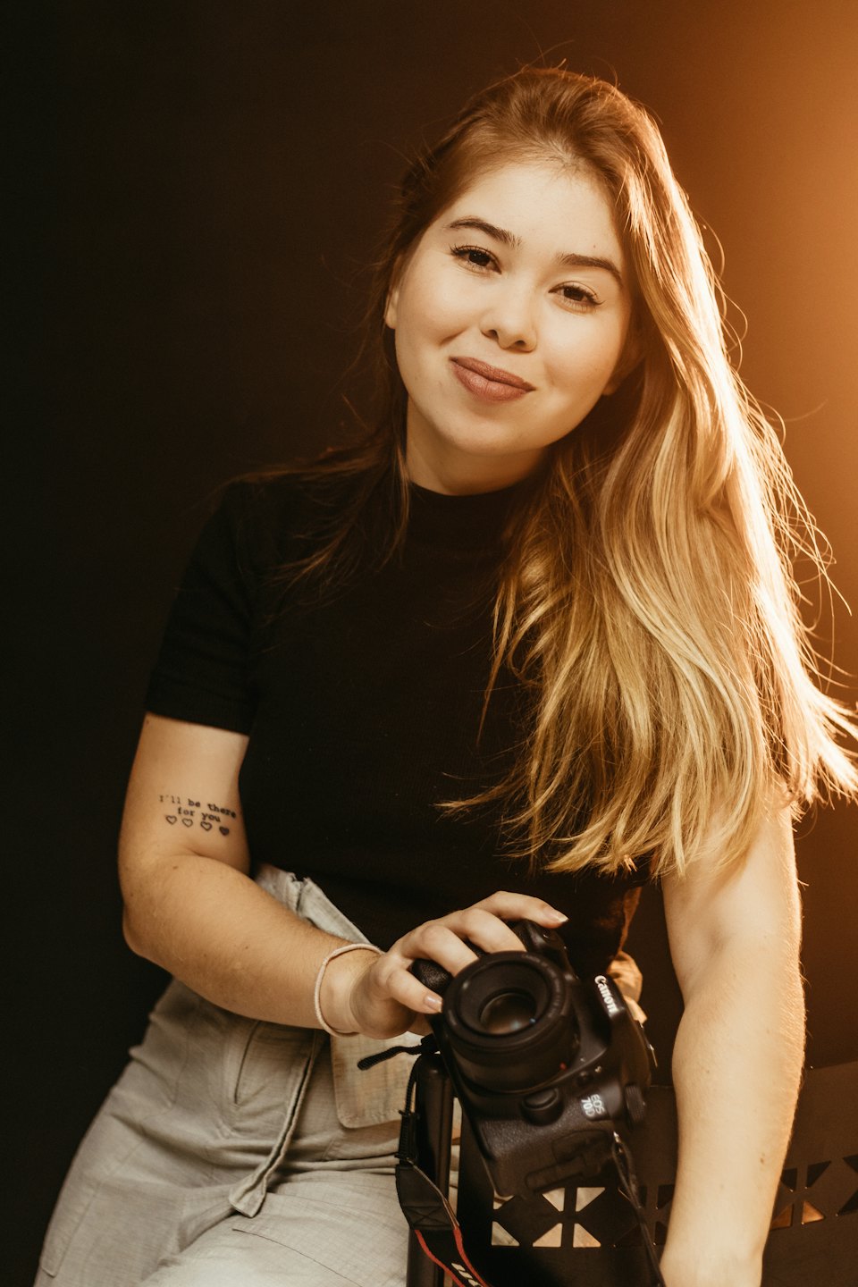 Uśmiechnięta kobieta trzymająca profesjonalny aparat fotograficzny.